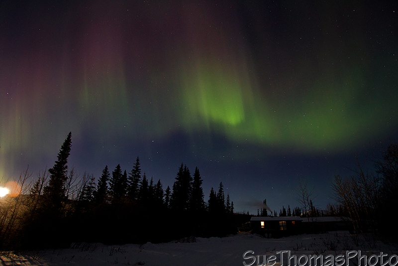 Northern Lights over the cabin with the moon